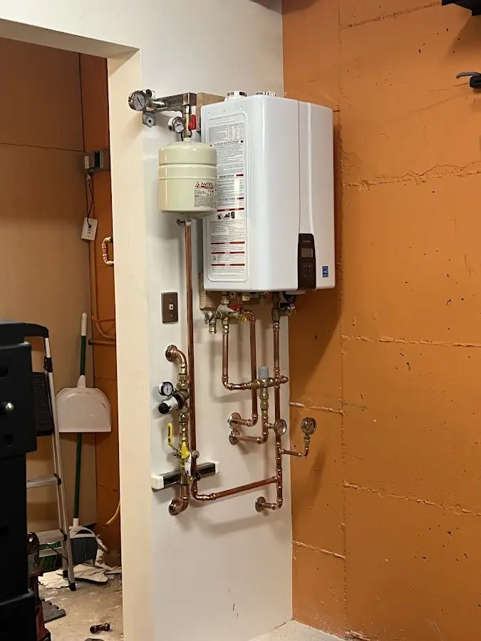 Plumbing technician inspecting water heater connections in Tiverton